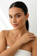 Mujer con cola usando Pulsera Karma Oro 18K y aretes dorados